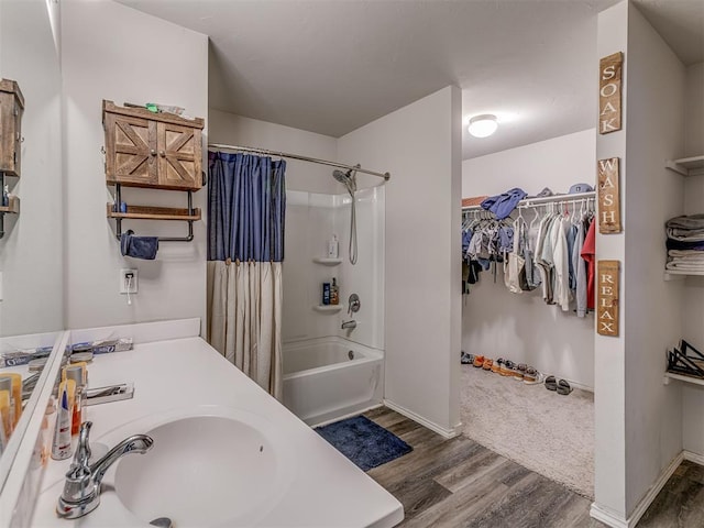 full bathroom with baseboards, shower / tub combo with curtain, wood finished floors, a walk in closet, and vanity