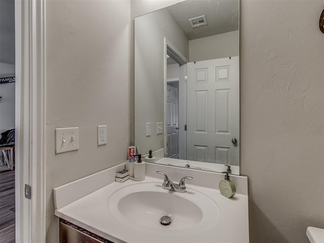 bathroom with a textured wall, vanity, and visible vents