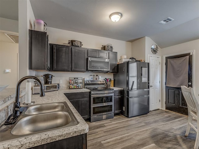 42056 Cadens Trl, Shawnee, OK 74804 - kitchen featuring stainless steel appliances, light countertops, light wood-style floors, and lofted ceiling