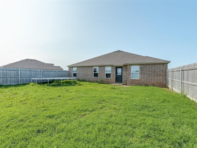 42056 Cadens Trl, Shawnee, OK 74804 - rear view of house with a trampoline, a fenced backyard, and brick siding