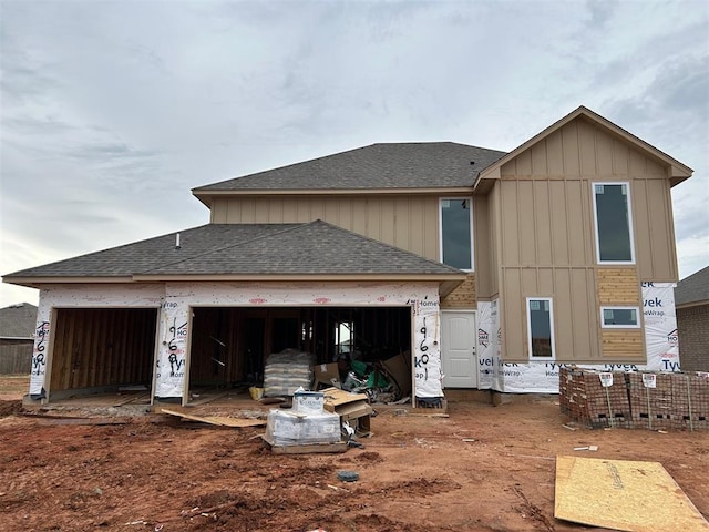 rear view of property featuring board and batten siding, roof with shingles, and a garage