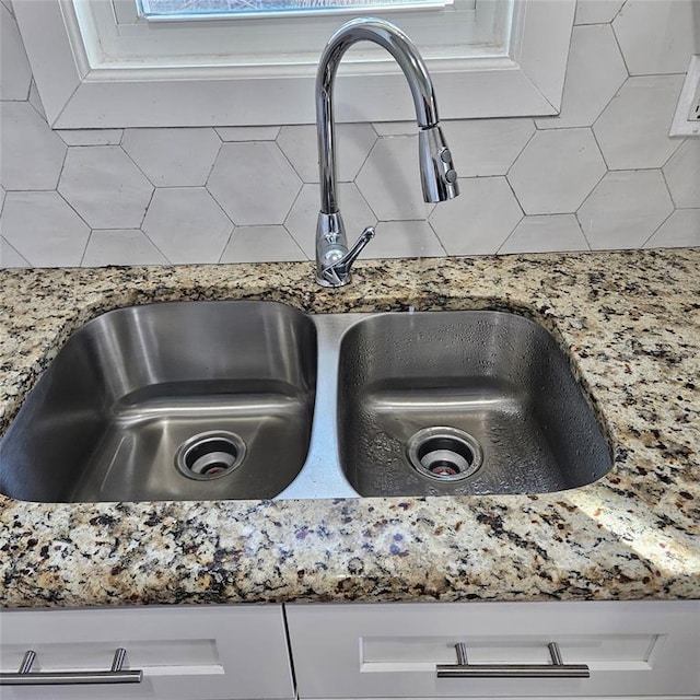 interior details with stone counters, white cabinetry, and a sink