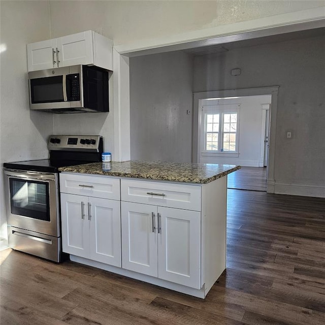 kitchen featuring stone counters, dark wood finished floors, appliances with stainless steel finishes, white cabinets, and baseboards