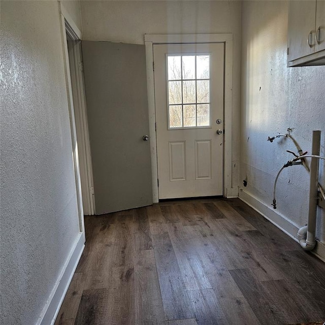 doorway to outside with a textured wall and dark wood-type flooring