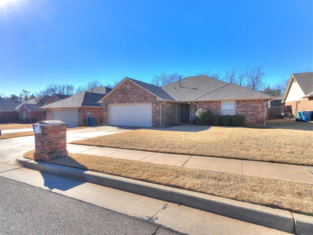 709 Taber Ln, Edmond, OK 73003 - ranch-style home featuring an attached garage, brick siding, a shingled roof, driveway, and a front yard