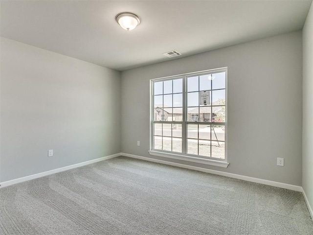 carpeted spare room with visible vents and baseboards