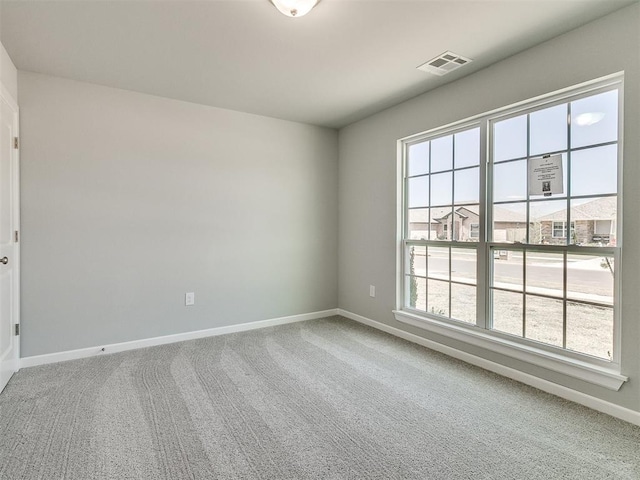 carpeted empty room featuring visible vents and baseboards