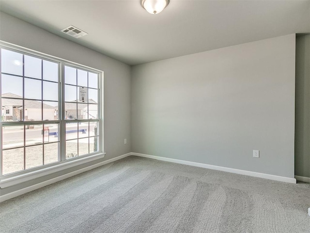 carpeted empty room featuring baseboards and visible vents