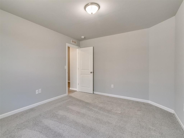 carpeted spare room featuring baseboards and visible vents