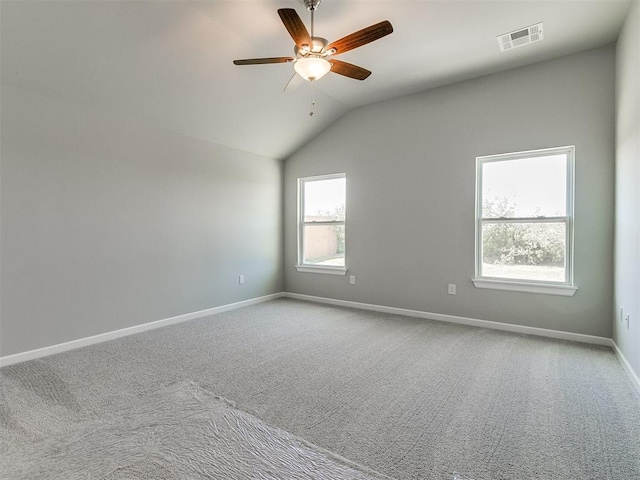 carpeted spare room with lofted ceiling, visible vents, ceiling fan, and baseboards