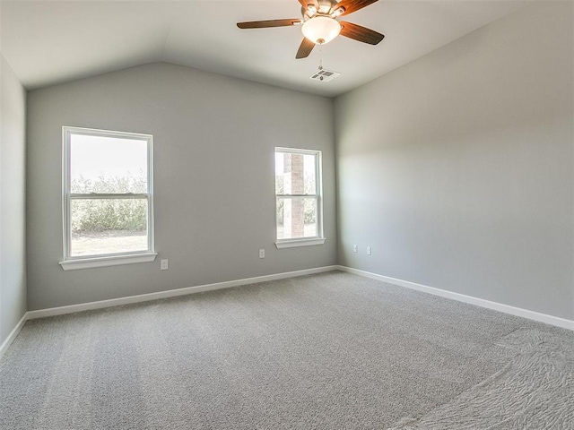 empty room featuring lofted ceiling, carpet floors, a ceiling fan, visible vents, and baseboards