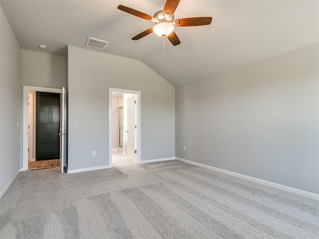 unfurnished bedroom with lofted ceiling, light colored carpet, visible vents, ensuite bathroom, and baseboards