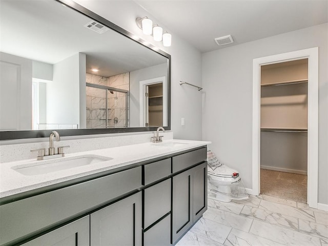 bathroom featuring marble finish floor, a spacious closet, and a sink
