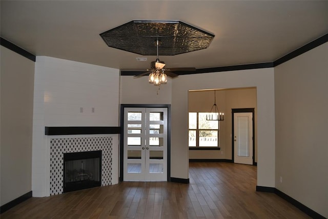 1525 NW 17th Pl, Newcastle, OK 73065 - unfurnished living room featuring wood finished floors, baseboards, ceiling fan, a tiled fireplace, and french doors