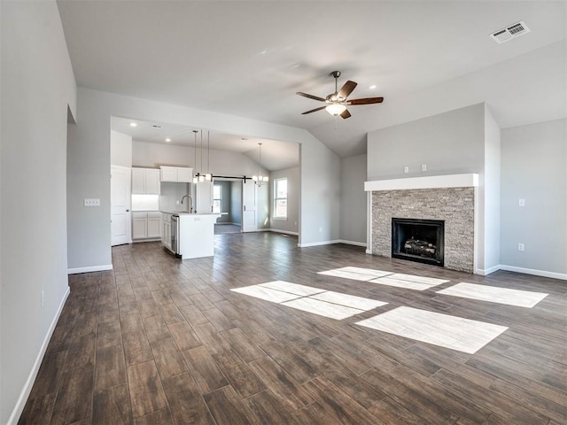 unfurnished living room with dark wood-type flooring, a sink, visible vents, a ceiling fan, and vaulted ceiling