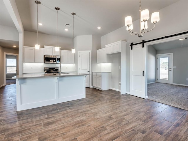 kitchen featuring an island with sink, white cabinetry, appliances with stainless steel finishes, and pendant lighting