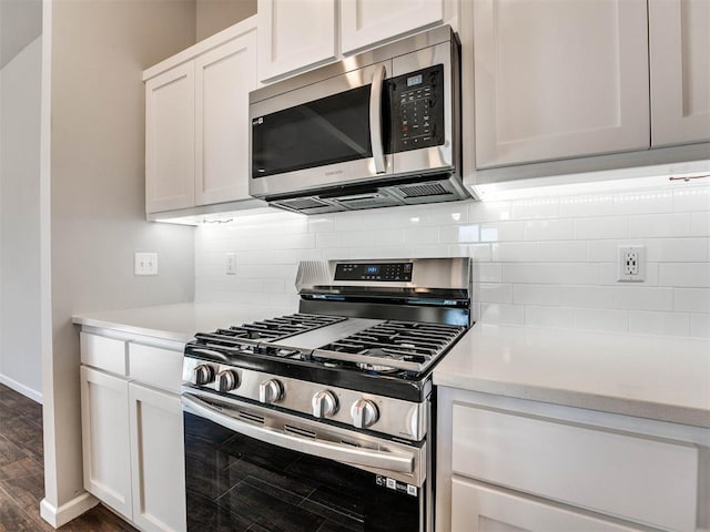 kitchen featuring tasteful backsplash, white cabinetry, stainless steel appliances, and light countertops