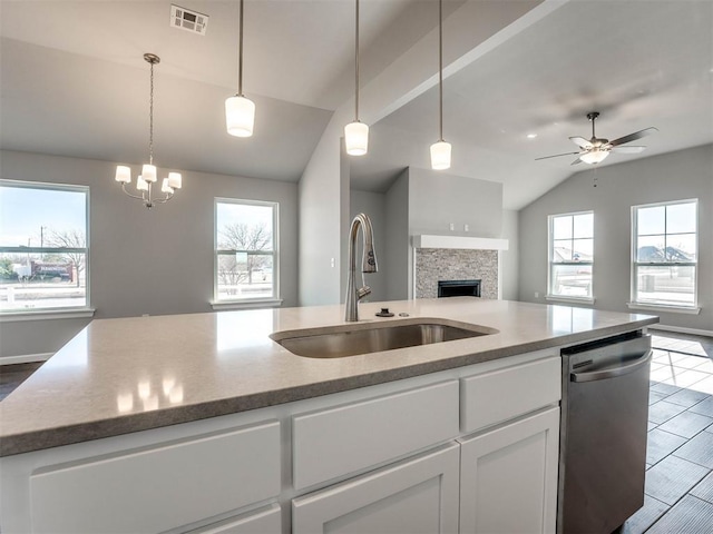 kitchen featuring visible vents, open floor plan, stainless steel dishwasher, white cabinetry, and a sink