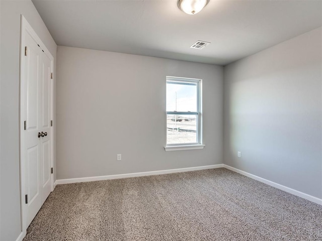 empty room featuring carpet floors, visible vents, and baseboards