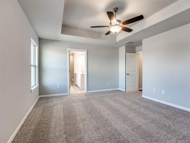 unfurnished bedroom featuring light carpet, a raised ceiling, visible vents, and baseboards