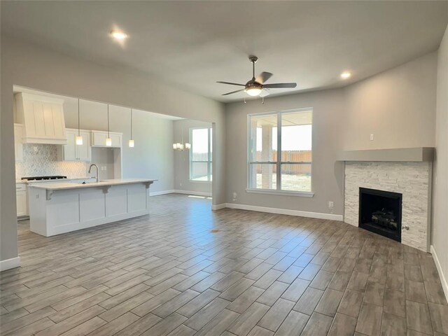 unfurnished living room featuring baseboards, a ceiling fan, and wood finished floors