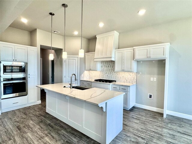 kitchen featuring white cabinets, a sink, baseboards, tasteful backsplash, and custom exhaust hood