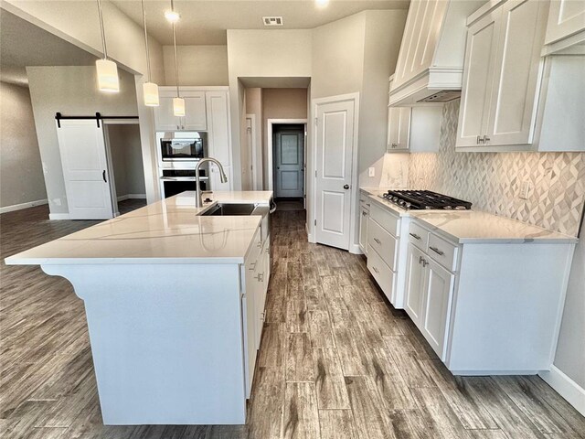 kitchen with stainless steel appliances, wood finished floors, visible vents, a sink, and custom exhaust hood