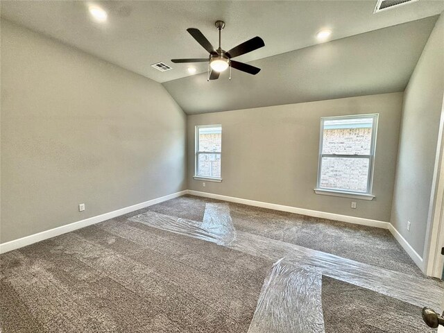 empty room with carpet flooring, vaulted ceiling, baseboards, visible vents, and a ceiling fan