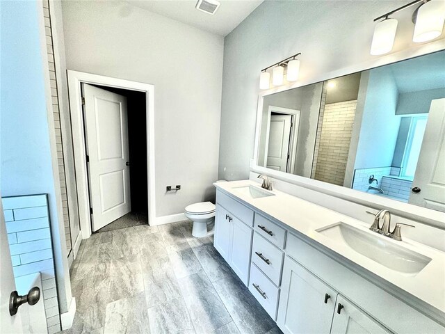bathroom with double vanity, visible vents, toilet, and a sink