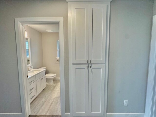 bathroom featuring toilet, vanity, and baseboards