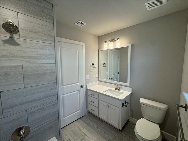 bathroom featuring baseboards, visible vents, vanity, and toilet