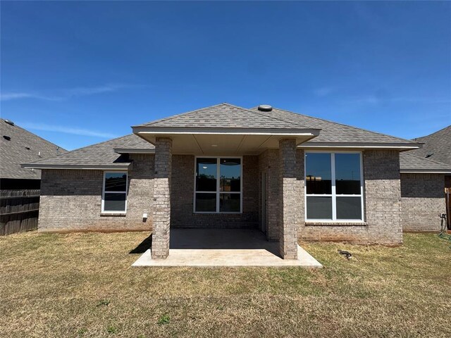 back of house with a patio area, roof with shingles, and brick siding