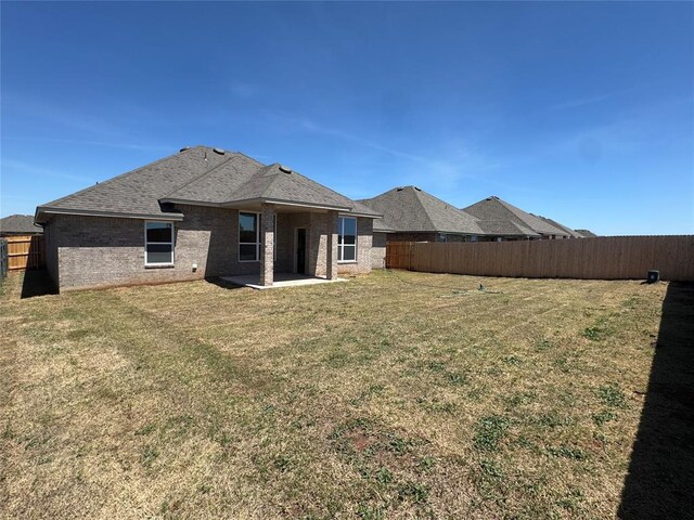 rear view of house featuring a fenced backyard, a yard, a patio area, and brick siding