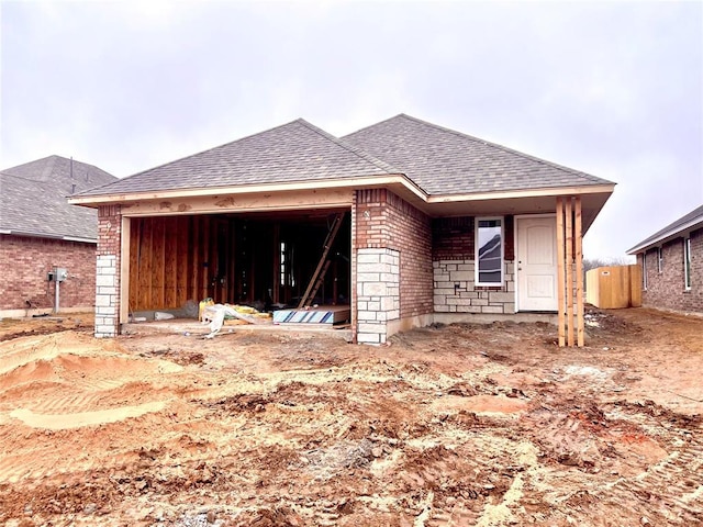 exterior space featuring a garage, a shingled roof, and brick siding