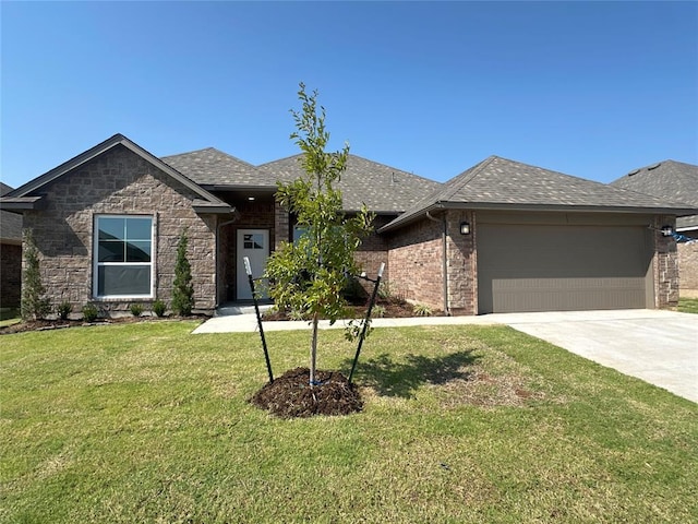 view of front of house with an attached garage, concrete driveway, roof with shingles, and a front yard