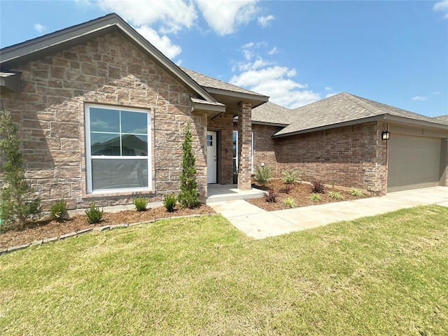 view of front of home featuring a shingled roof, a front yard, stone siding, and a garage