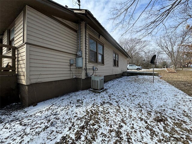 view of snow covered exterior with central AC
