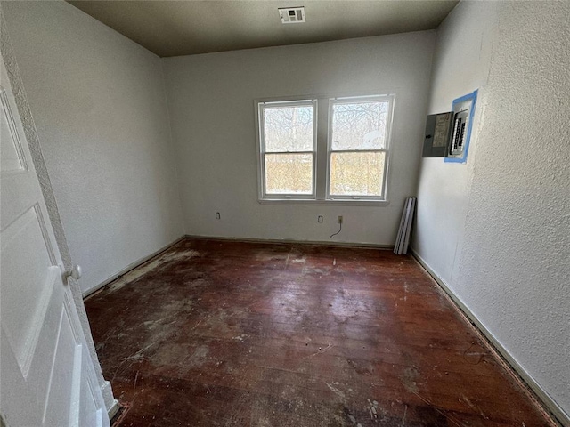 spare room featuring visible vents, wood finished floors, and a textured wall