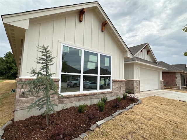 view of home's exterior with stone siding, board and batten siding, concrete driveway, a shingled roof, and a garage