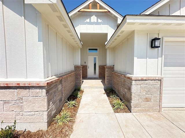 doorway to property with brick siding, board and batten siding, and an attached garage