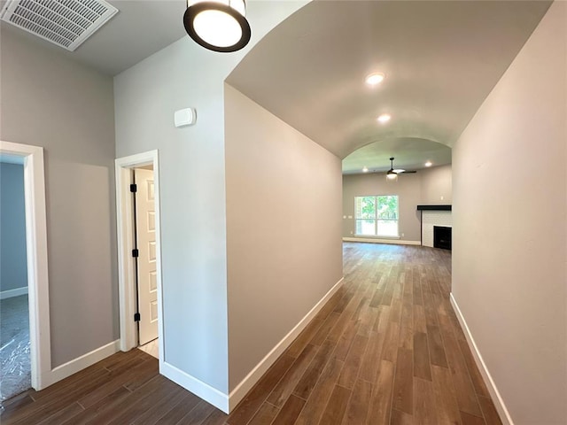 hall featuring arched walkways, visible vents, baseboards, and dark wood-style flooring