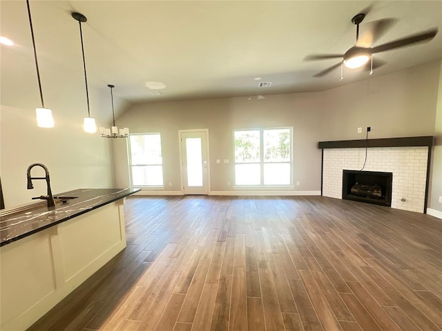 unfurnished living room with visible vents, baseboards, dark wood finished floors, a fireplace, and ceiling fan