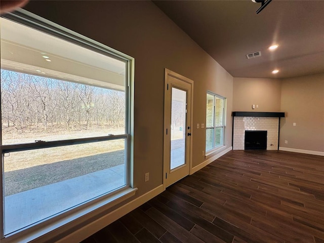 unfurnished living room with visible vents, baseboards, recessed lighting, dark wood-style flooring, and a brick fireplace