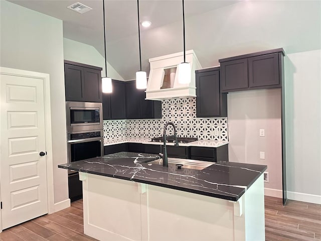 kitchen with wood finished floors, visible vents, backsplash, and stainless steel appliances