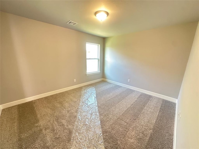 spare room with carpet, visible vents, and baseboards