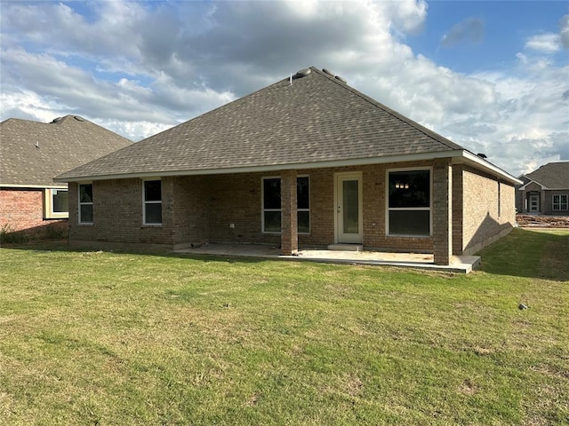 rear view of house featuring a yard, a patio, and roof with shingles