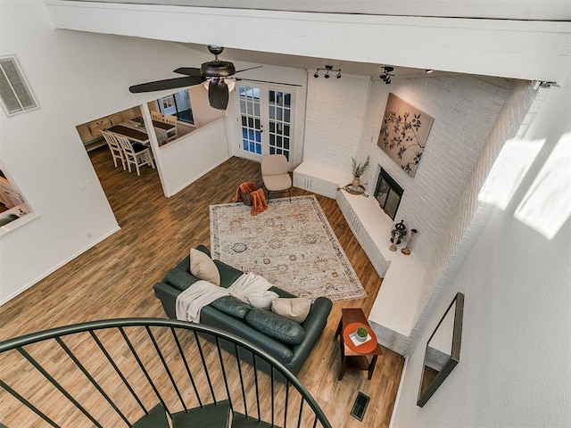 living room featuring a brick fireplace, visible vents, wood finished floors, and french doors