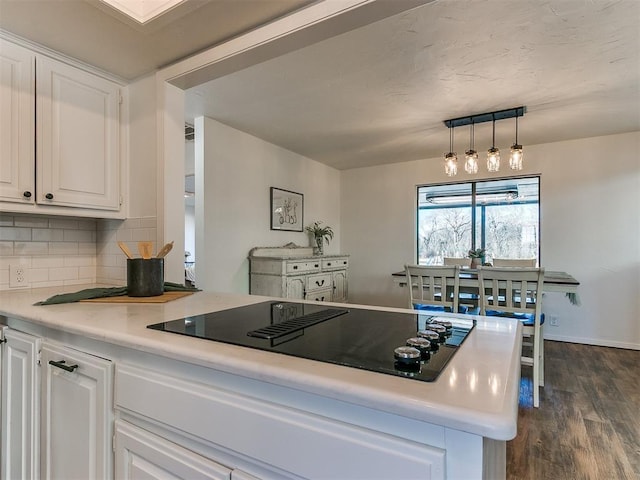 kitchen with decorative backsplash, dark wood-style floors, black electric cooktop, light countertops, and white cabinetry