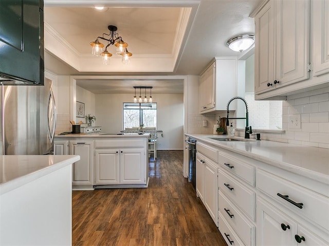 kitchen featuring a sink, light countertops, freestanding refrigerator, dark wood-style floors, and a tray ceiling