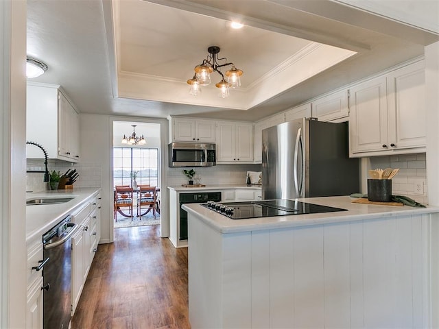 kitchen with black appliances, a chandelier, a raised ceiling, and a sink